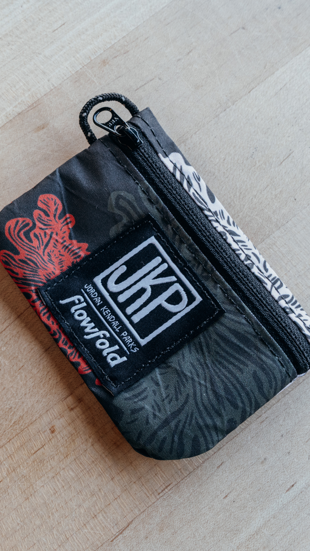 Small pouch with a brand logo on a wooden surface