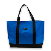 Blue tote bag with black handles and trim on a white background