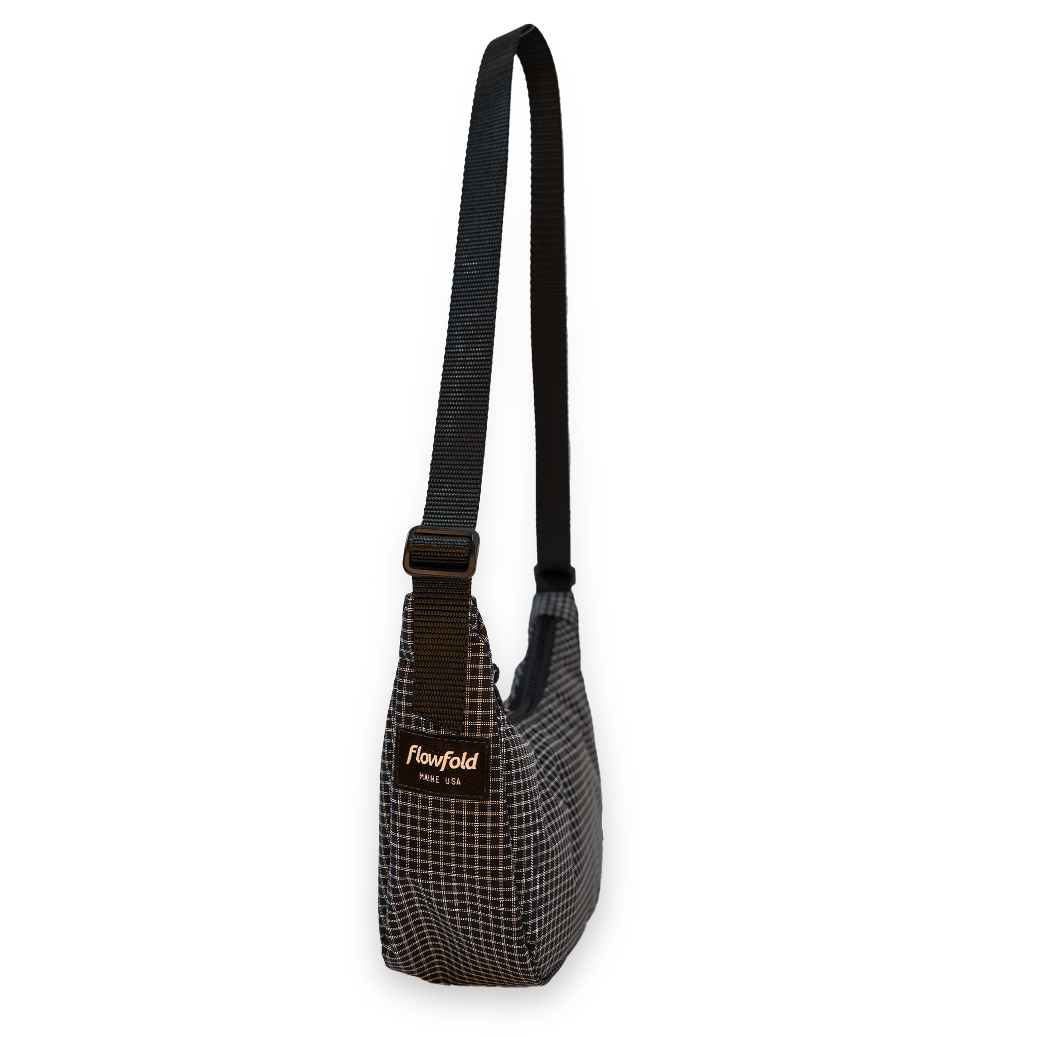 Small crossbody bag with a grid pattern and black strap on a white background